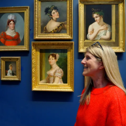 A guide standing in front of paintings in the blue picture gallery