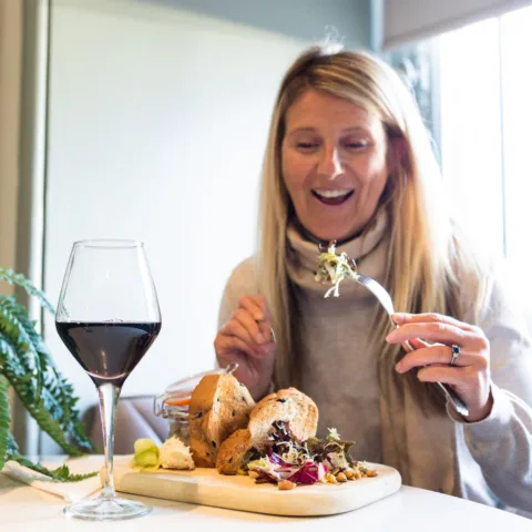 Image of a person eating lunch with a glass of red wine