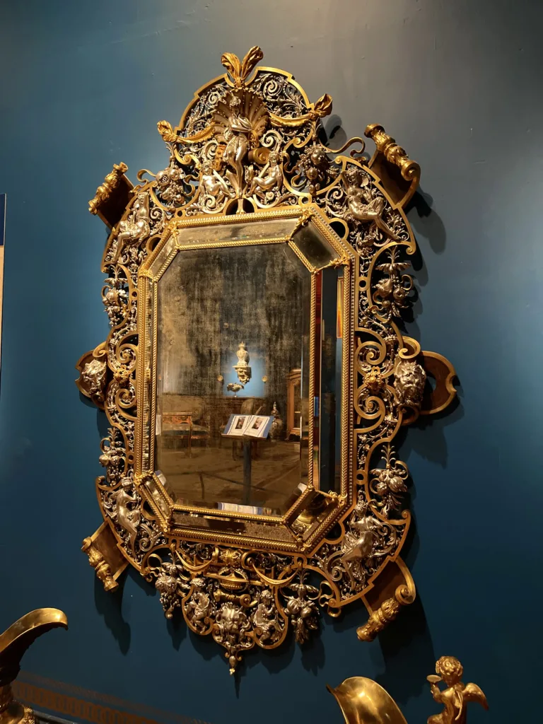 Image of a mirror with a very intricate metal work as a frame