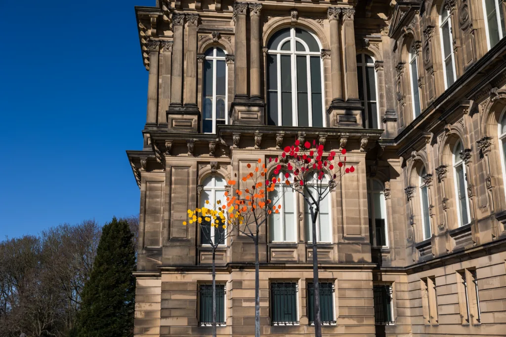 Metal tree art installations sited outside of a historical French-style museum