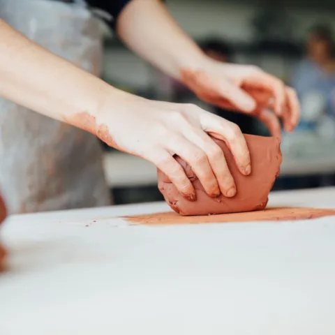 Person handling clay on a bench