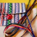 Small bag made of cotton and patterned with various styles of needlework using multicoloured thread.