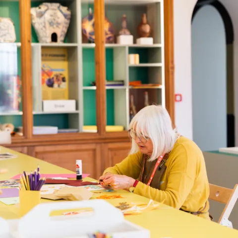 Lady in a yellow jumper working on a mixed-media craft activity in a museum gallery