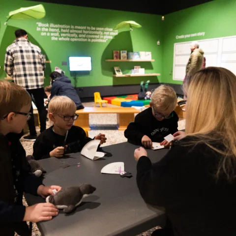 Woman with children completing a craft activity in a museum gallery