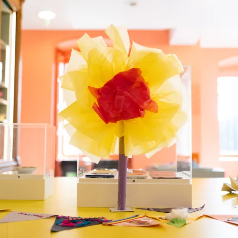 A yellow and red flower made out of tissue paper.