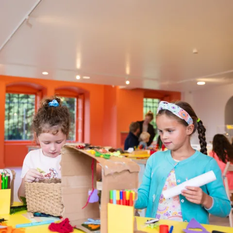 Two young girls using carboard to create art in the Create Space.