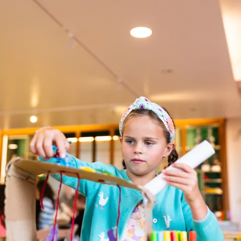 A young girl constructing a cardboard design.