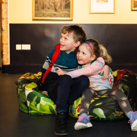 Two children, a boy and a girl, sat on bean bags in the conversation space.