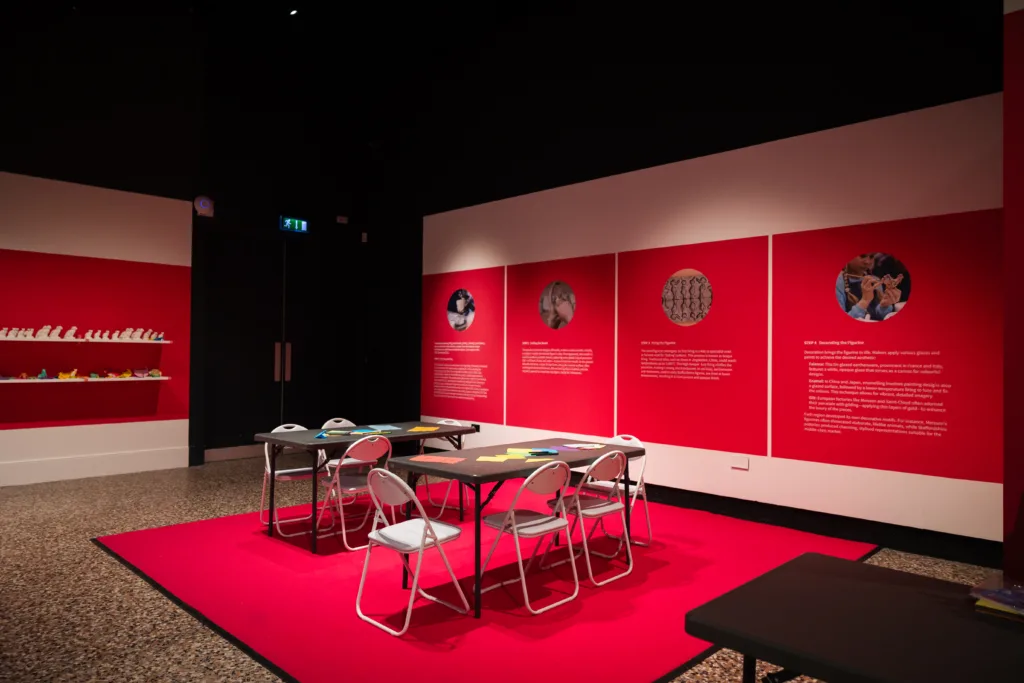 Museum exhibition room with pink walls and a space to create.
