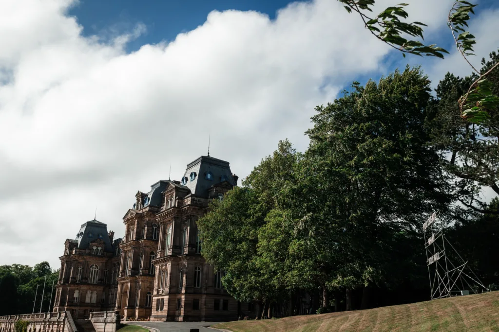 A light installation reading "YOU CREATE WHAT YOU WILL" by Nathan Coley, set against the historic Bowes Museum grounds.
