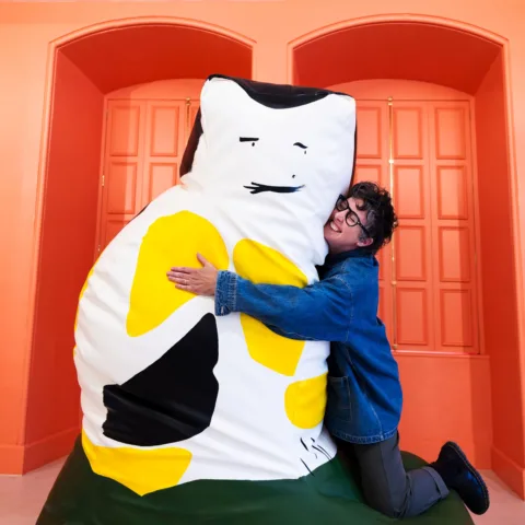 Pippa Hale hugging a giant cat black, white and yellow squishee