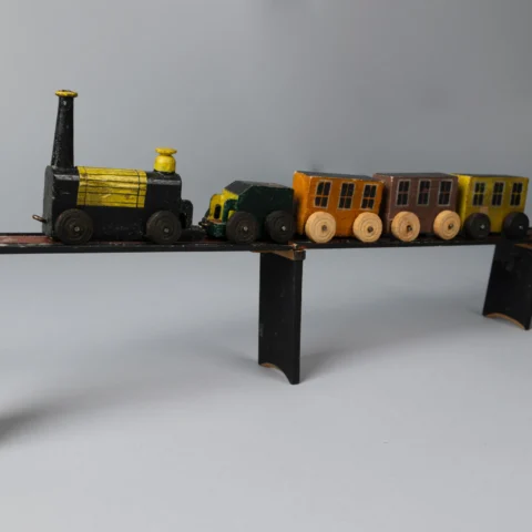 A vintage wooden toy train set featuring a black and yellow locomotive with several colourful passenger cars displayed on a raised track.