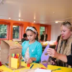 A girl and her mum doings crafts in the create space.