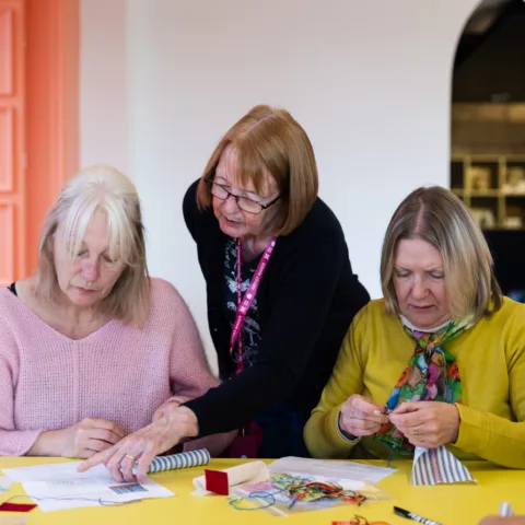 An artist leading a craft session with two women.