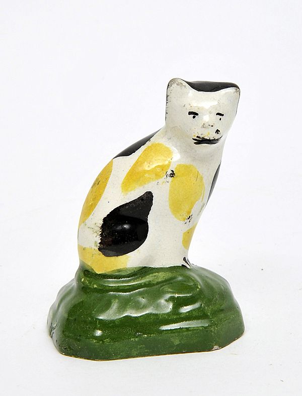 A small white, yellow and black cat ceramic