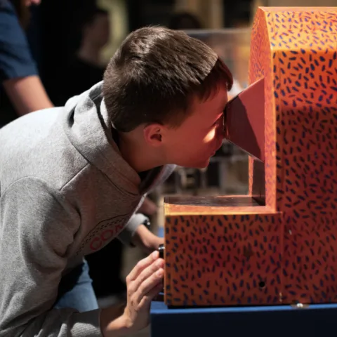 A young boy peering into a mechanical object