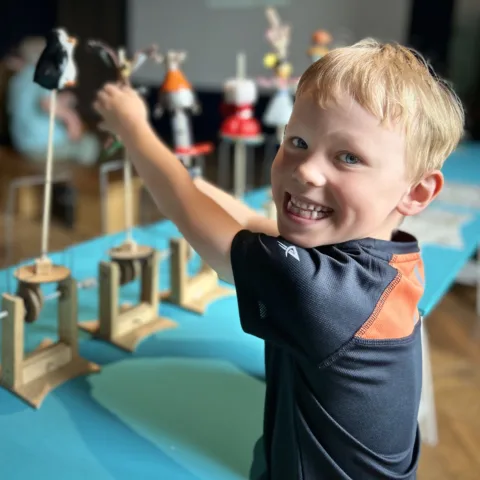 A young boy smiling at an automata workshop