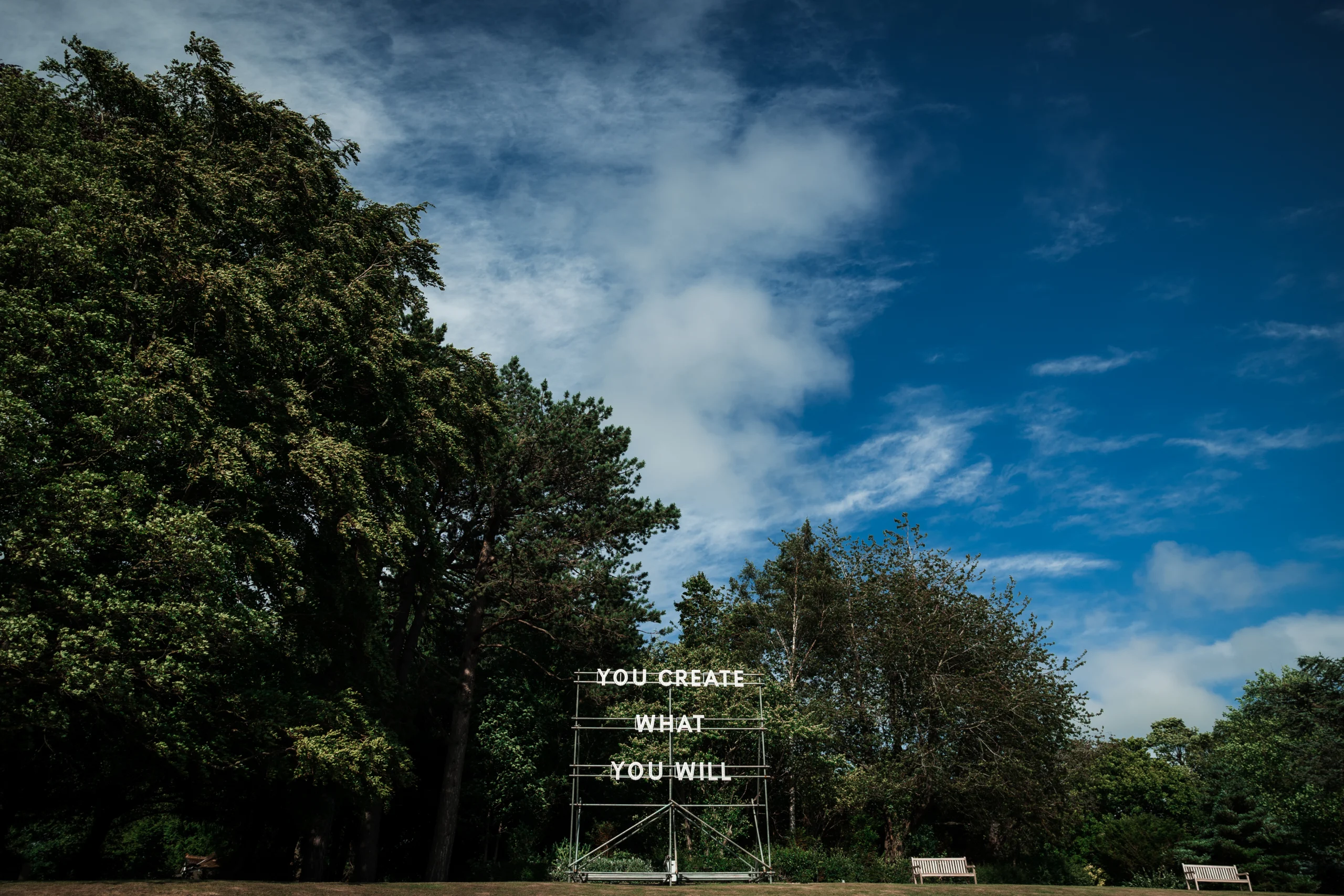 A light installation reading "YOU CREATE WHAT YOU WILL" by Nathan Coley, set against the historic Bowes Museum grounds.