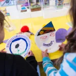 Two children holding their paper masks they made