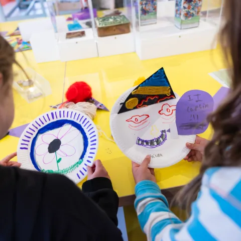 Two children holding their paper masks they made