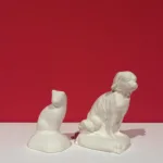 An example of a cat and dog bisque figurine against a pink background