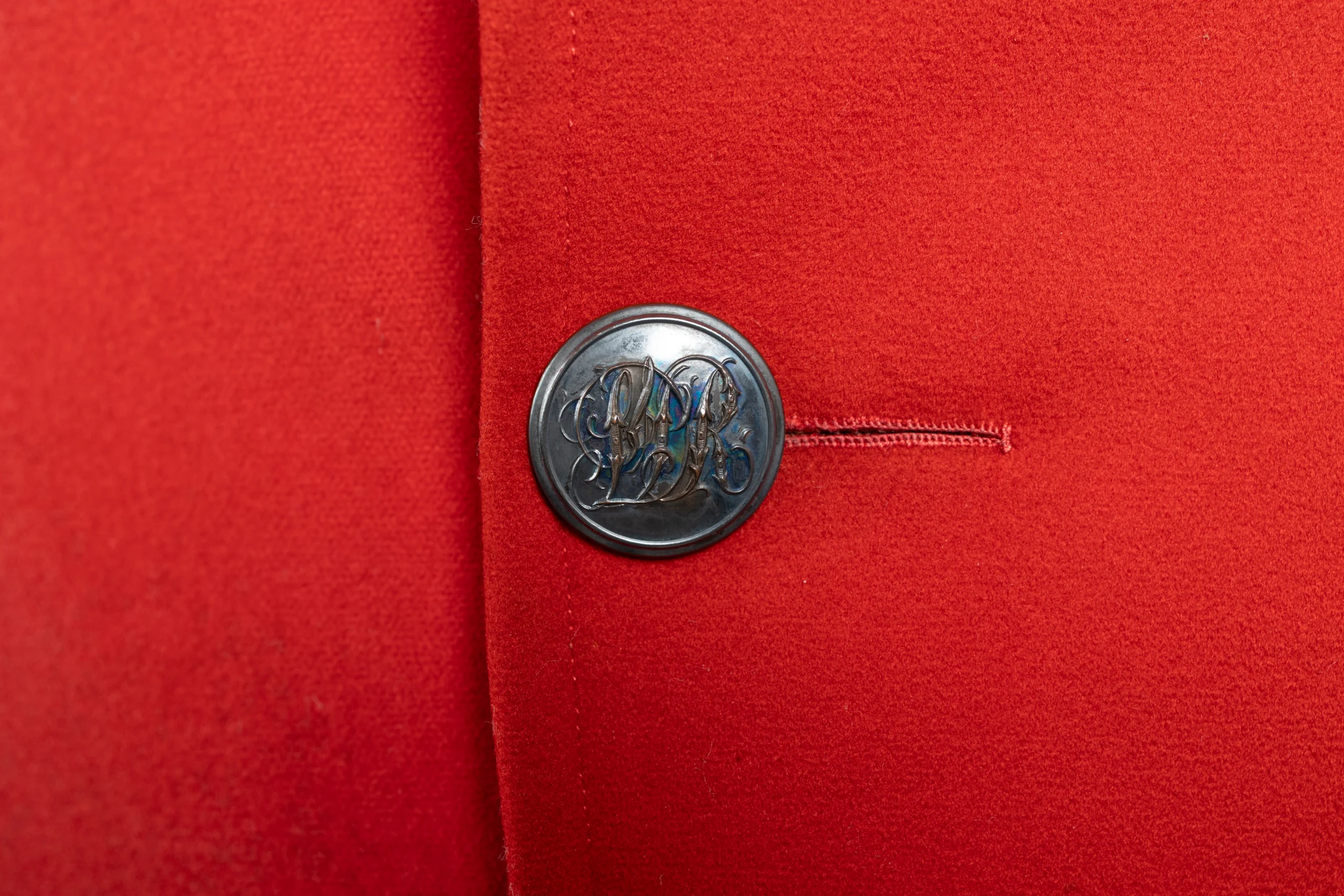 A close up short of an engraved button on a red jacket
