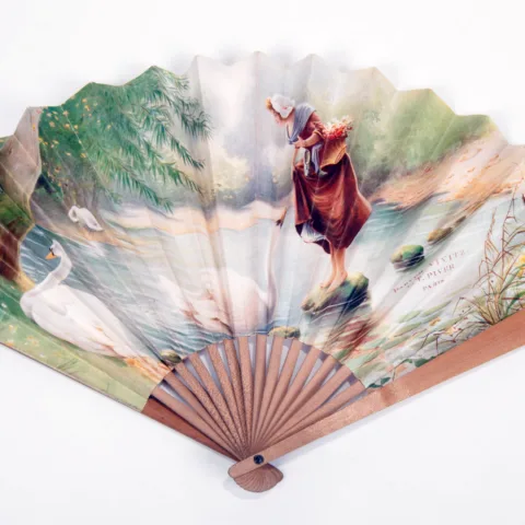 A fan with an image of a woman near a river, the fan is from the A Woman of Taste and Fashion exhibition