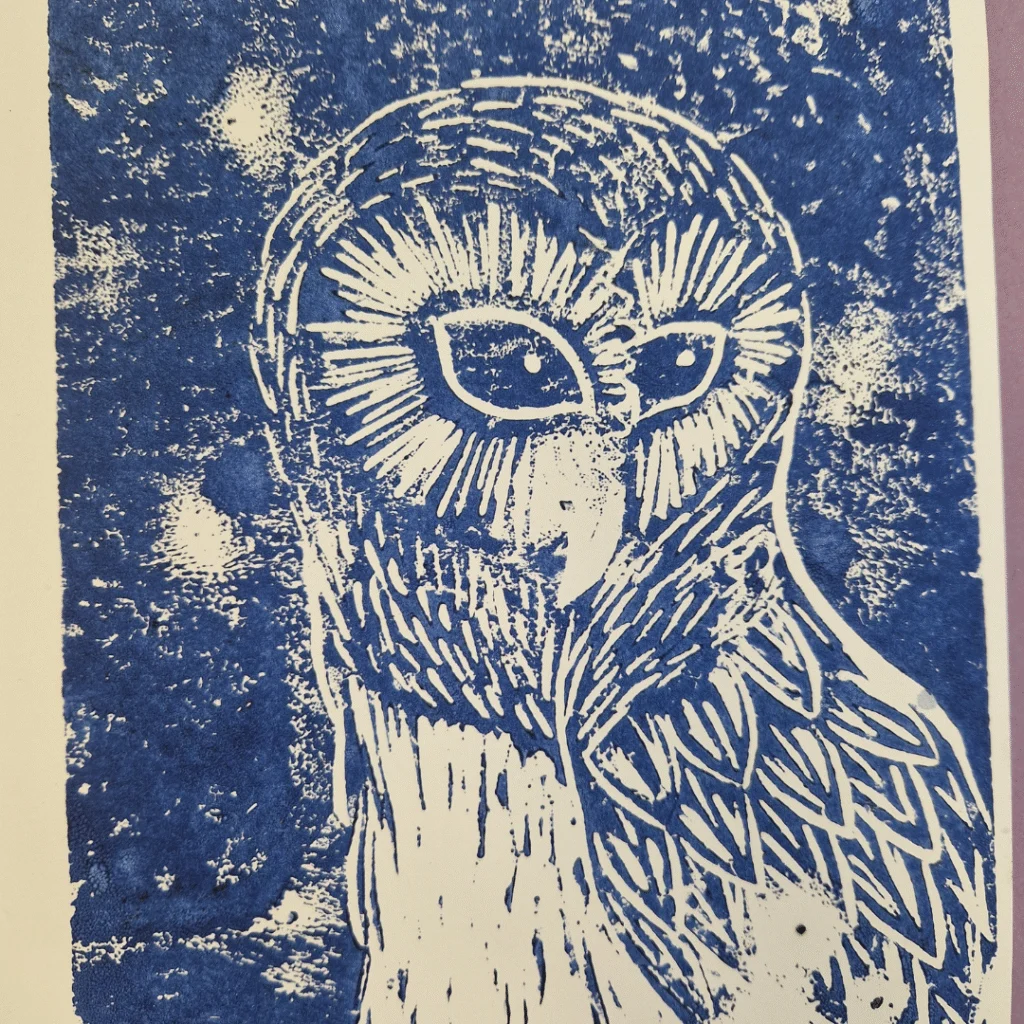 A blue block print of an owl with stylized feather details and radiating lines around its eyes, set against a textured background with white speckles resembling stars.